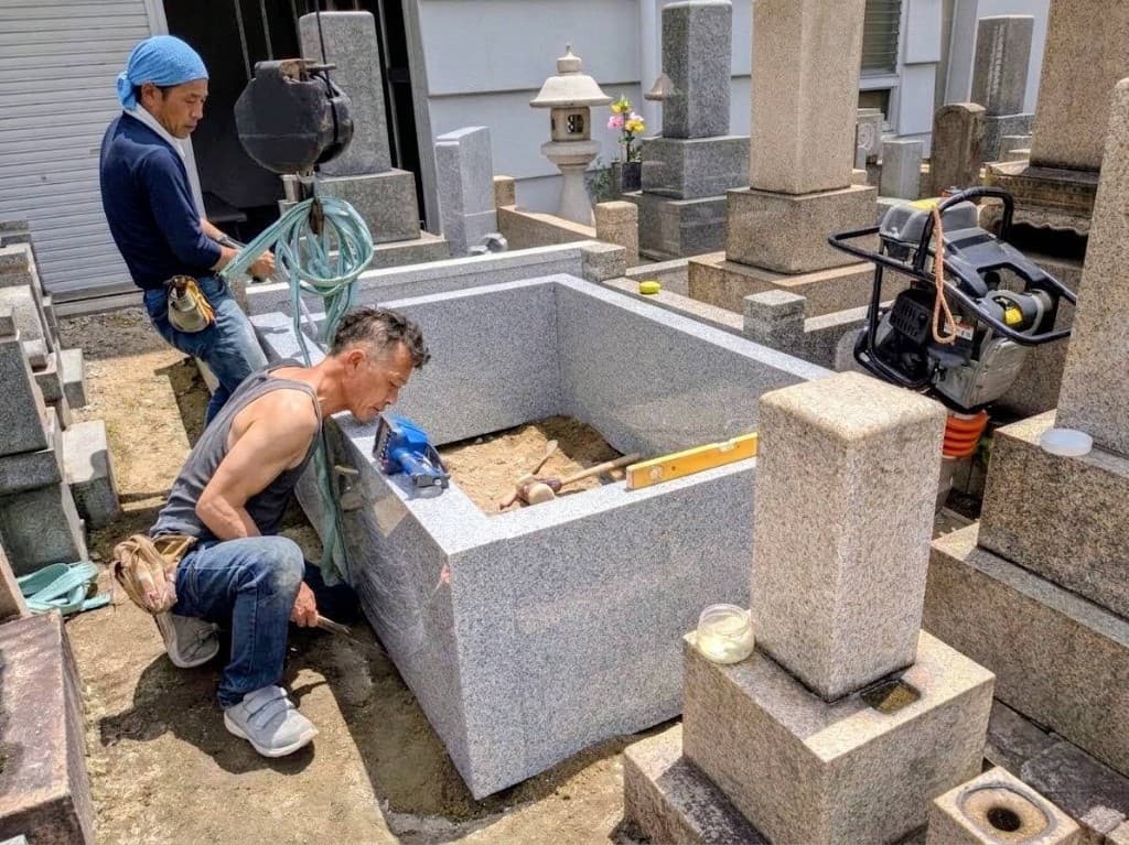 クレーンで石材を据え付ける職人